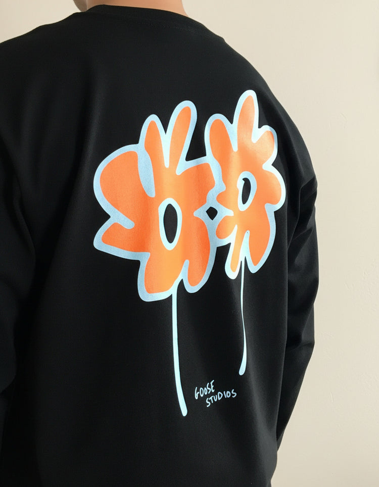 Black long sleeve t-shirt with orange and white floral design on the back, featuring 'Goose Studios' branding.
