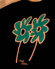 Two stylized flowers in orange and green printed on a black 240gsm t-shirt, featuring the text 'Goose Studios' logo beneath in a handwritten font.