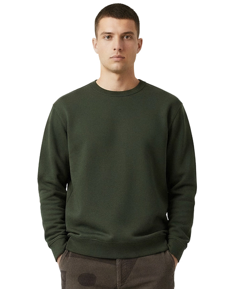 Man wearing an olive green organic cotton sweatshirt from organic clothing brand Goose Studios, together with patterned cord trousers from Patta