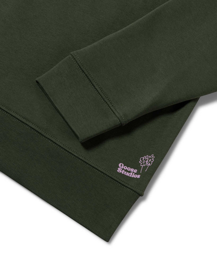Detail shot focussed on the organic cotton jersey in olive green of a men's sweatshirt by Goose Studios, who's screen printed logo in lilac can be seen, signifying a premium line from Goose Studios' collection