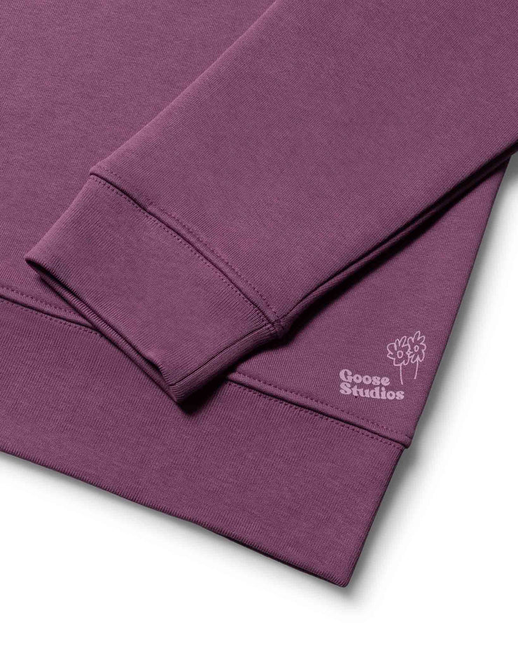 Organic cotton rib cuff detail of a mens organic cotton sweatshirt in Purple, also seen is a lilac logo of Goose Studios signifying a premium product from their catalogue of organic clothing
