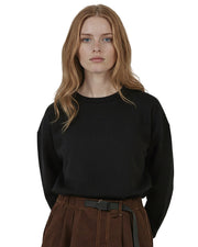 Woman wearing a black organic cotton sweatshirt from Goose Studios, together with brown trousers