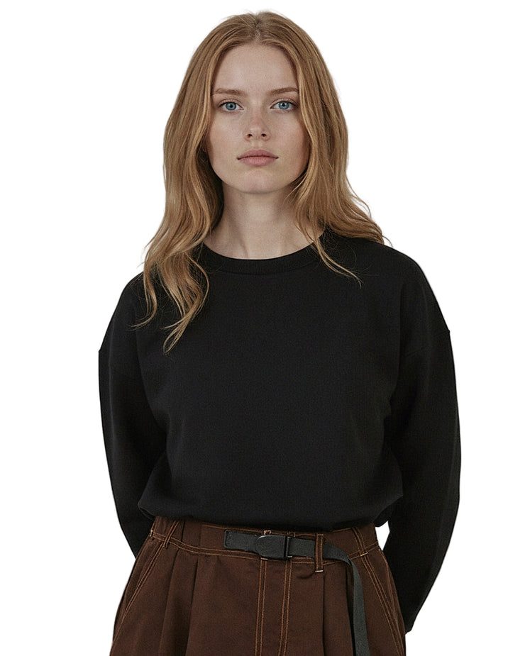 Woman wearing a black organic cotton sweatshirt from Goose Studios, together with brown trousers