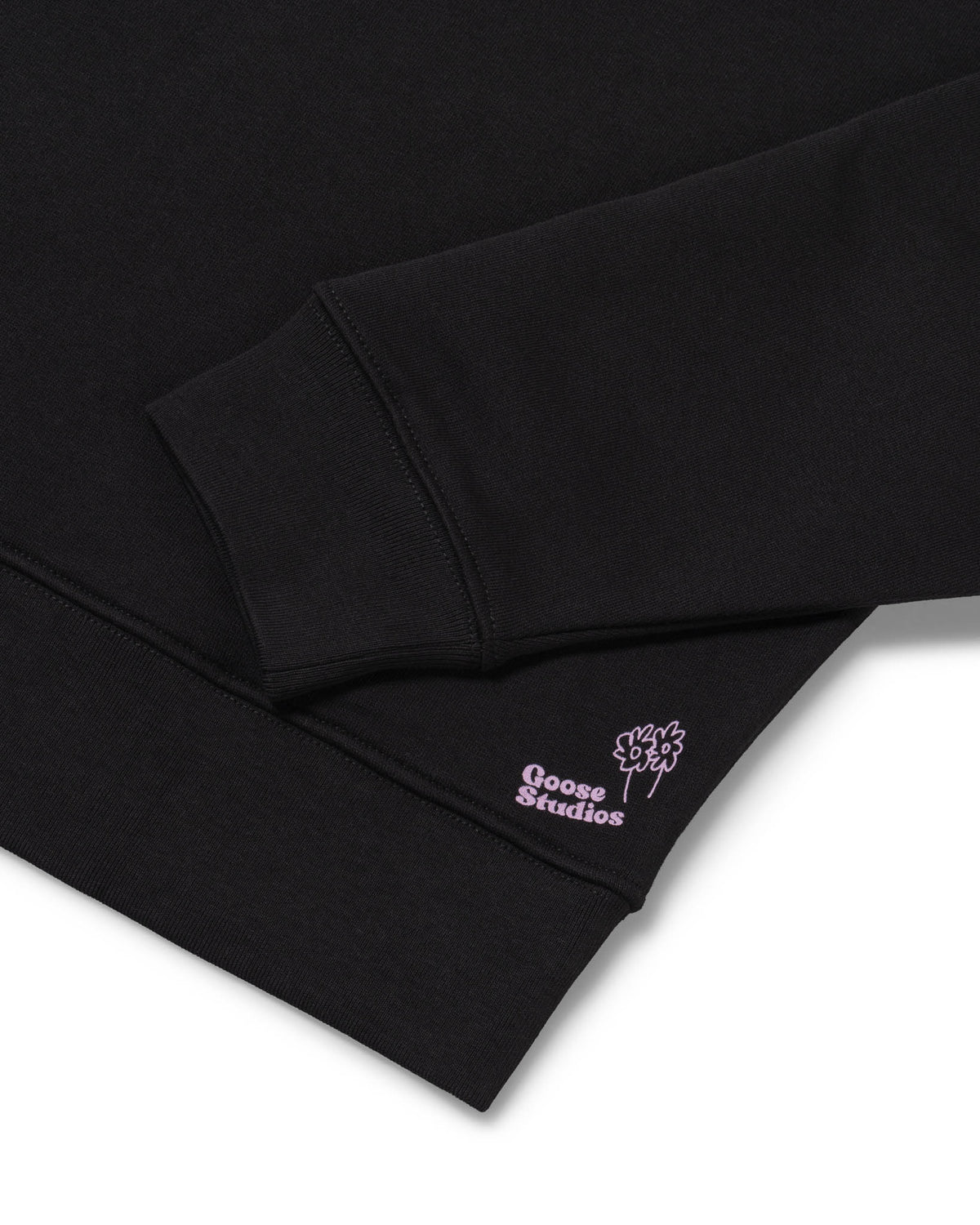 Cuff detail of women's organic cotton sweatshirt in black with small pink Goose Studios logo