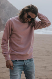 Man on a beach in Portugal wearing light jeans and an organic cotton sweatshirt from sustainable clothing brand Goose Studios