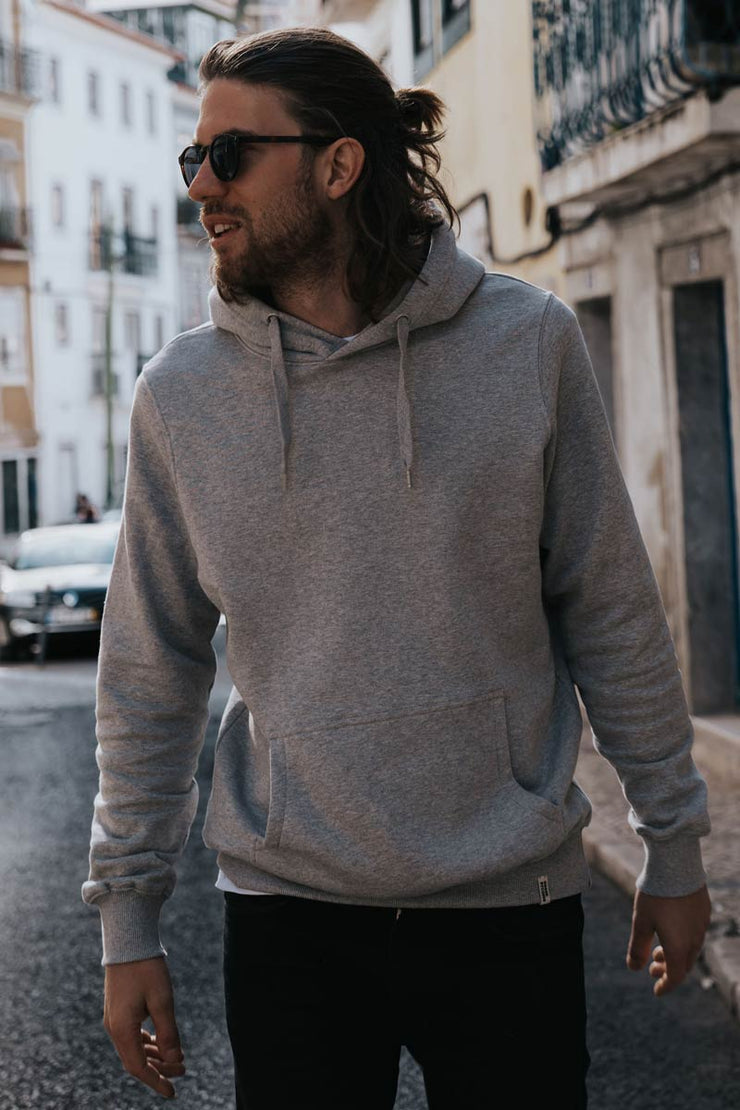 Man walking along a street in Lisbon wearing organic cotton hoodie with the hood down from sustainable clothing brand Goose Studios